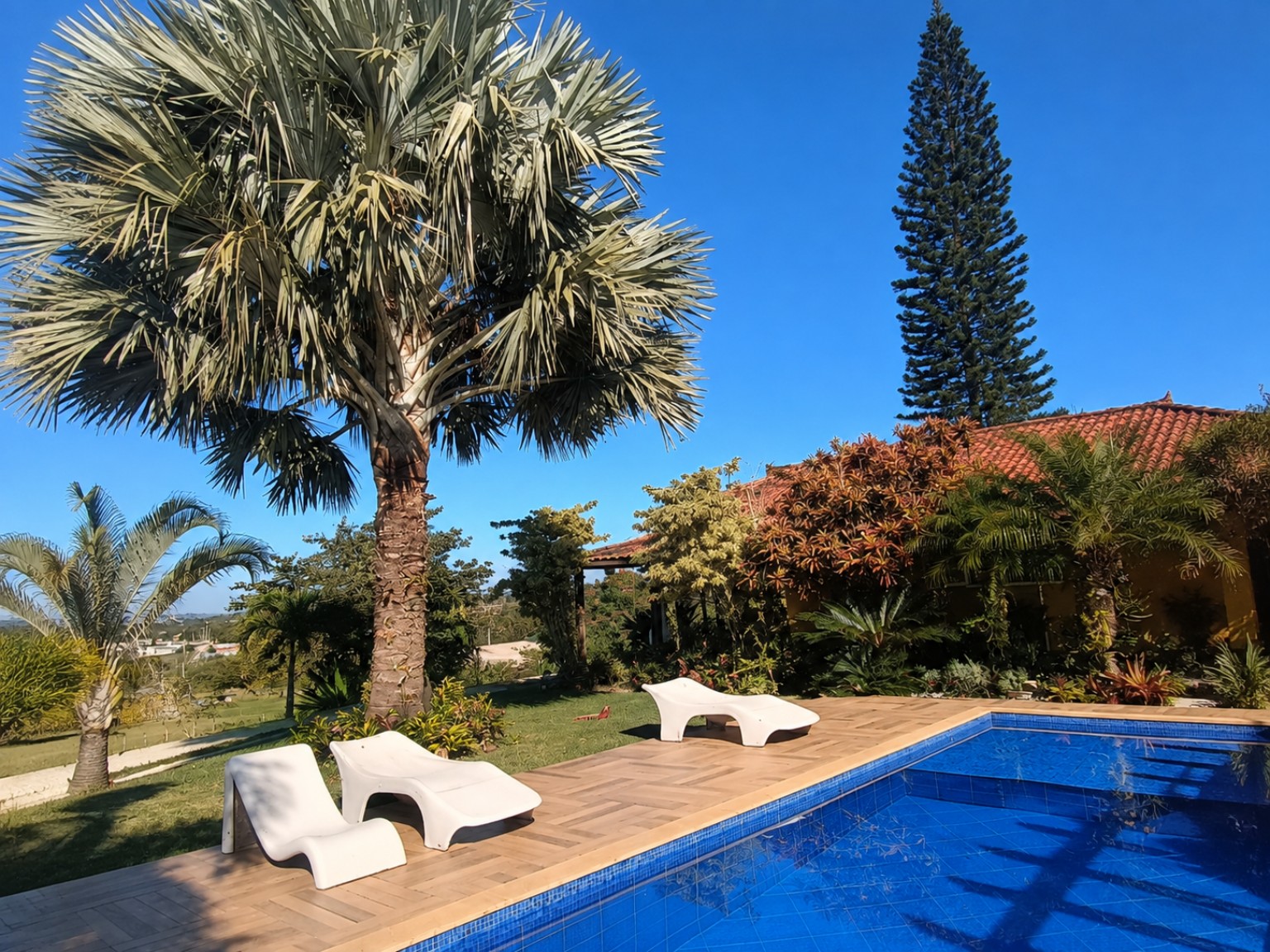 Piscina, jardim tropical e casa da Colina de Araruama sob o céu azul